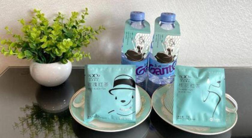 two bottles of water on a table with plates and a plant at Xana Hotelle Xiamen Airport Zone Government in Xiamen