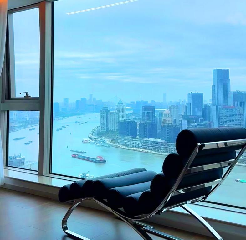 a chair in a room with a view of a city at Shanghai Skyline - Spacious&Elegant Luxury Apartment in Lujiazui near Shanghai Center Tower in Shanghai