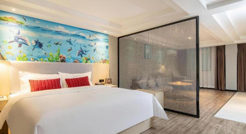 ein Schlafzimmer mit einem großen weißen Bett und einem Gemälde in der Unterkunft Borrman Hotel Dongguan Houjie Wanda Plaza Liaoxia Metro Station in Dongguan
