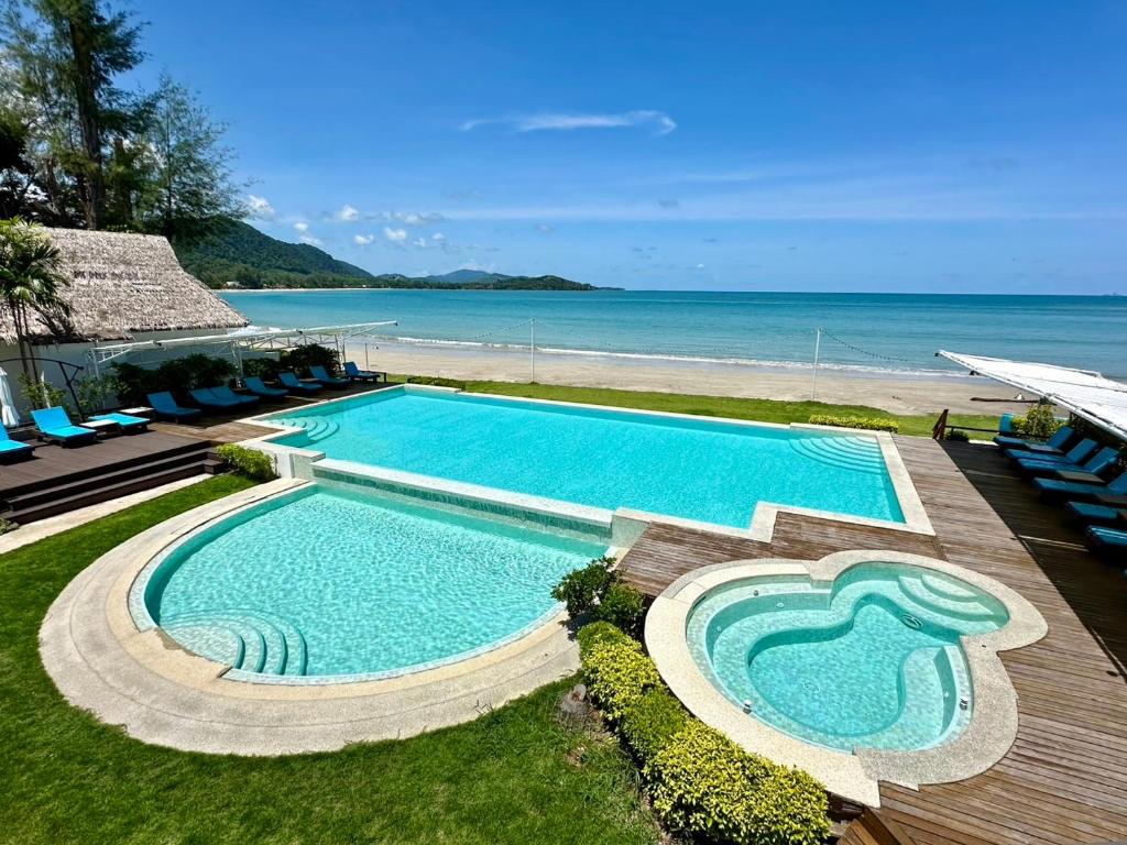 einen Pool neben einem Strand mit Stühlen in der Unterkunft Twin Bay Resort Koh Lanta in Ko Lanta