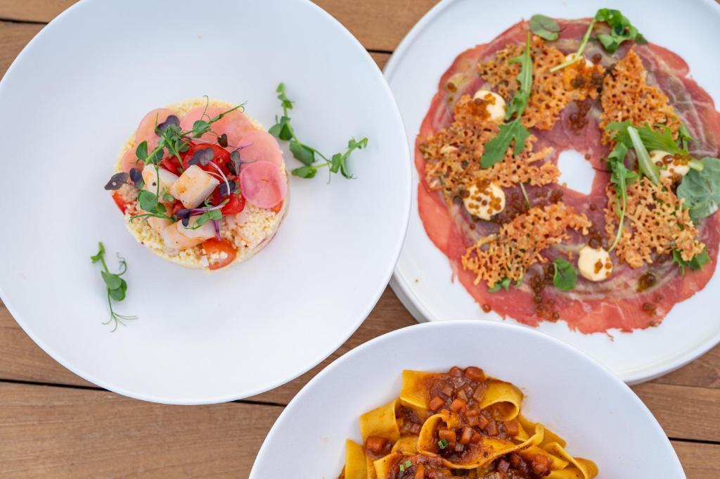 three plates of food on a wooden table at Sagredo Boutique Hotel & Spa in Ágios Fokás