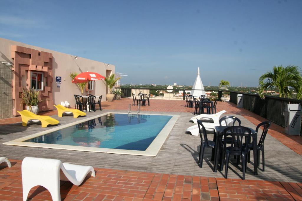 a patio with a pool and tables and chairs at Hotel Delta in Parnaíba