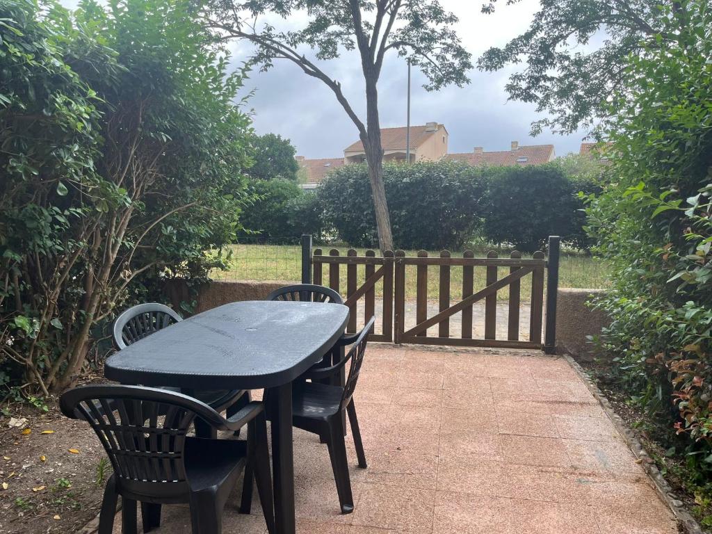 une table et des chaises noires à côté d'une clôture dans l'établissement T2 les patios de la mer saint cyprien, à Saint Cyprien Plage