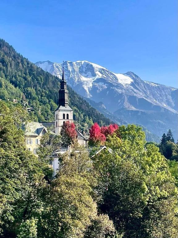 une église assise au sommet d'une colline avec des arbres dans l'établissement LE GL'ASSIE, à Saint-Gervais-les-Bains