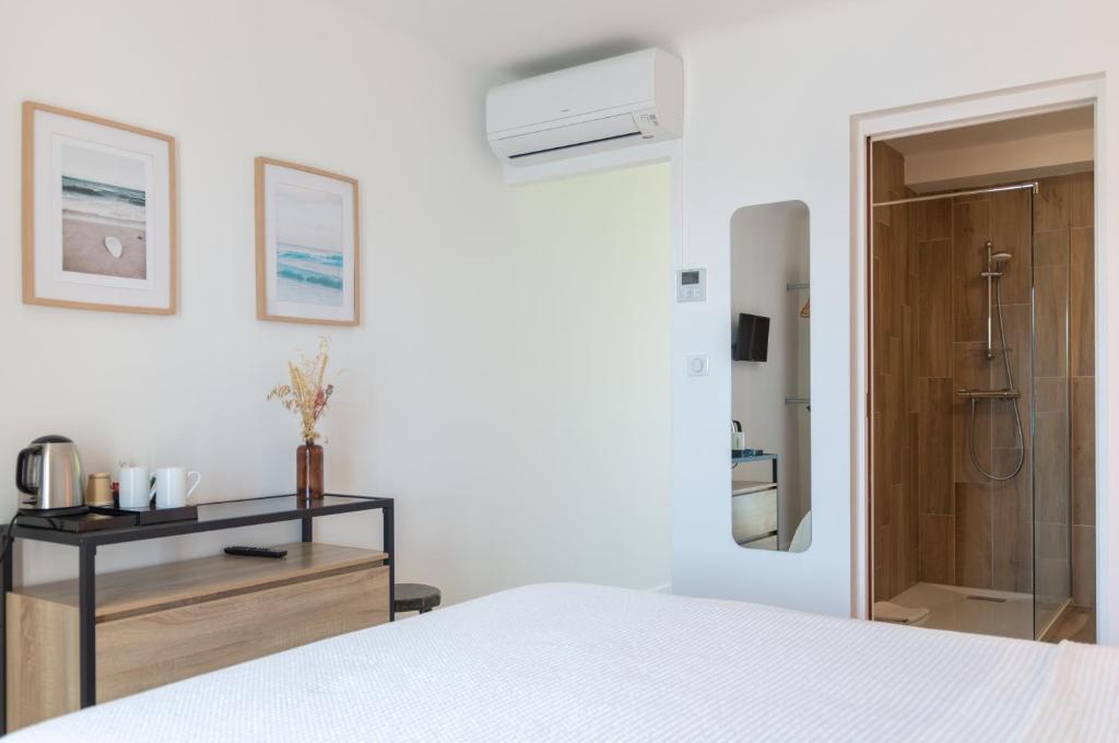 a white bedroom with a bed and a bathroom at HOTEL CAMPOMORO in Belvédère-Campomoro