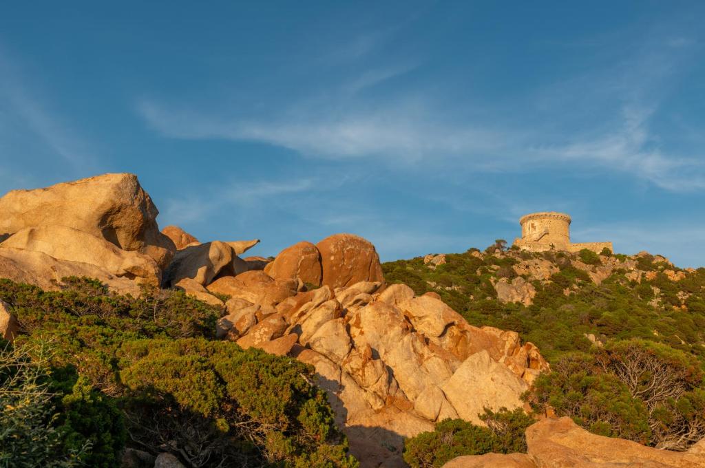 a pile of rocks with a lighthouse on a mountain at HOTEL CAMPOMORO in Belvédère-Campomoro