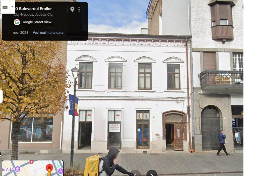 a person riding a bike in front of a white building at City Center apartment -A in Cluj-Napoca