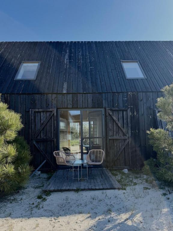 a building with a table and chairs in front of it at Svencele mini cottage apartment in Svencelė