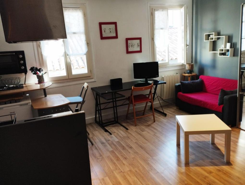 un salon avec un canapé rouge et une table dans l'établissement idéal festival joli studio climatisé, à Avignon