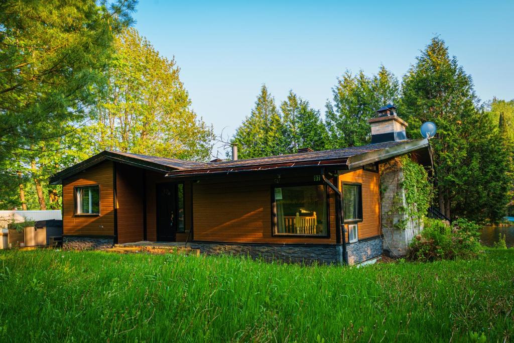 a small house in the middle of a field at Le Chalet Brun, jacuzzi en bord de lac in Saint Adolphe D'Howard