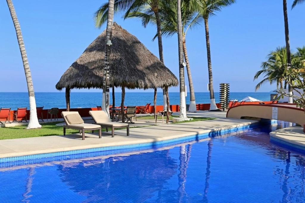 a swimming pool with chairs and palm trees and the ocean at Villa Sophie 3BR3BA Beachfront Terrace Heated Pool New Listing in Sayulita