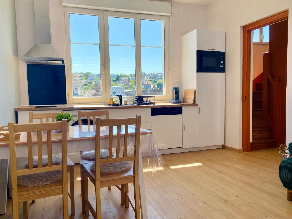 una cucina con tavolo, sedie e frigorifero di L'éclat à trois pas de la mer a Ault