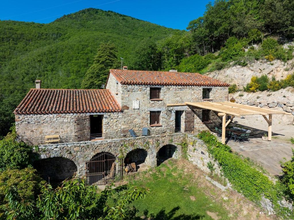 une vieille maison en pierre sur une colline avec un pont dans l'établissement Grand mas catalan en pleine nature avec piscine, à Céret