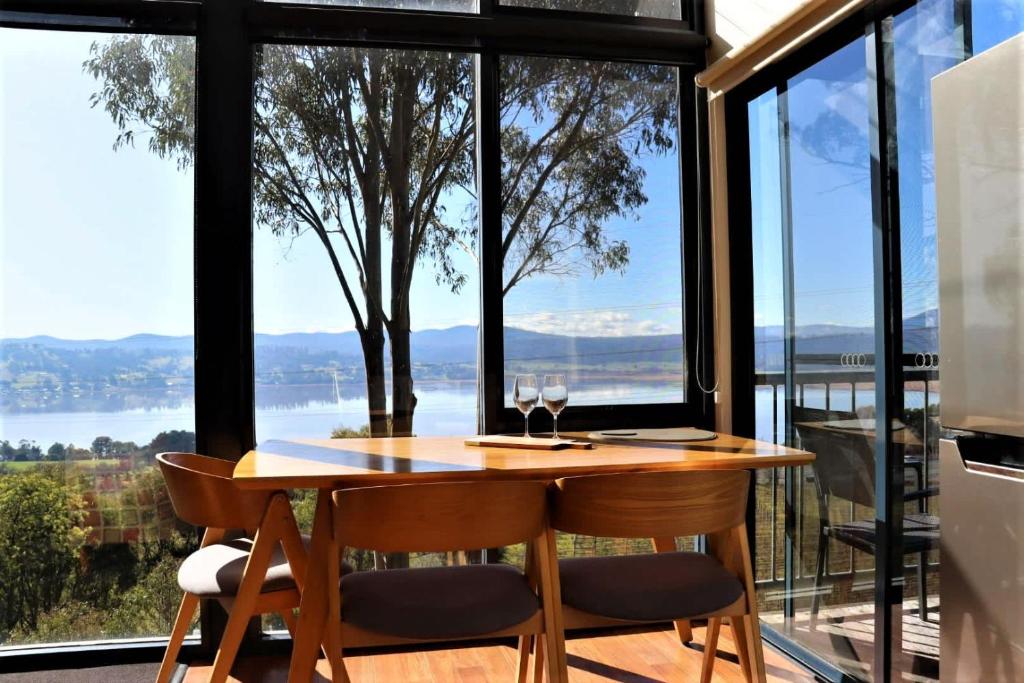 a dining room with a table and chairs and large windows at The Tamar Ridge Lookout at Tamar Ridge Apartments in Grindelwald