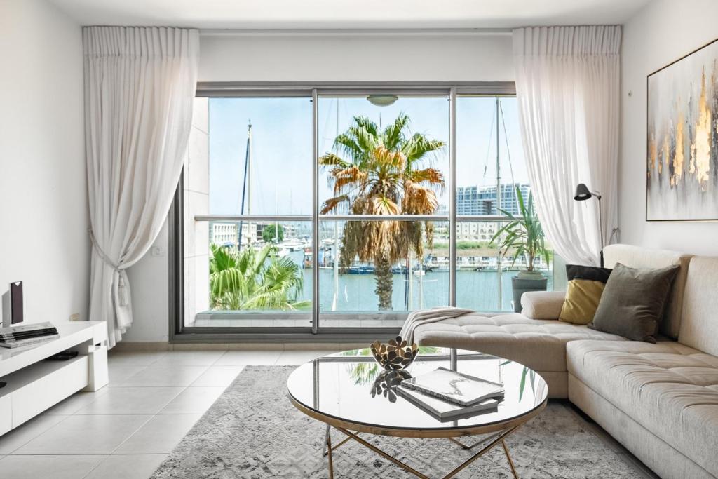 a living room with a couch and a glass table at Marina Waterfront Haven by Sea N Rent in Herzliyya B