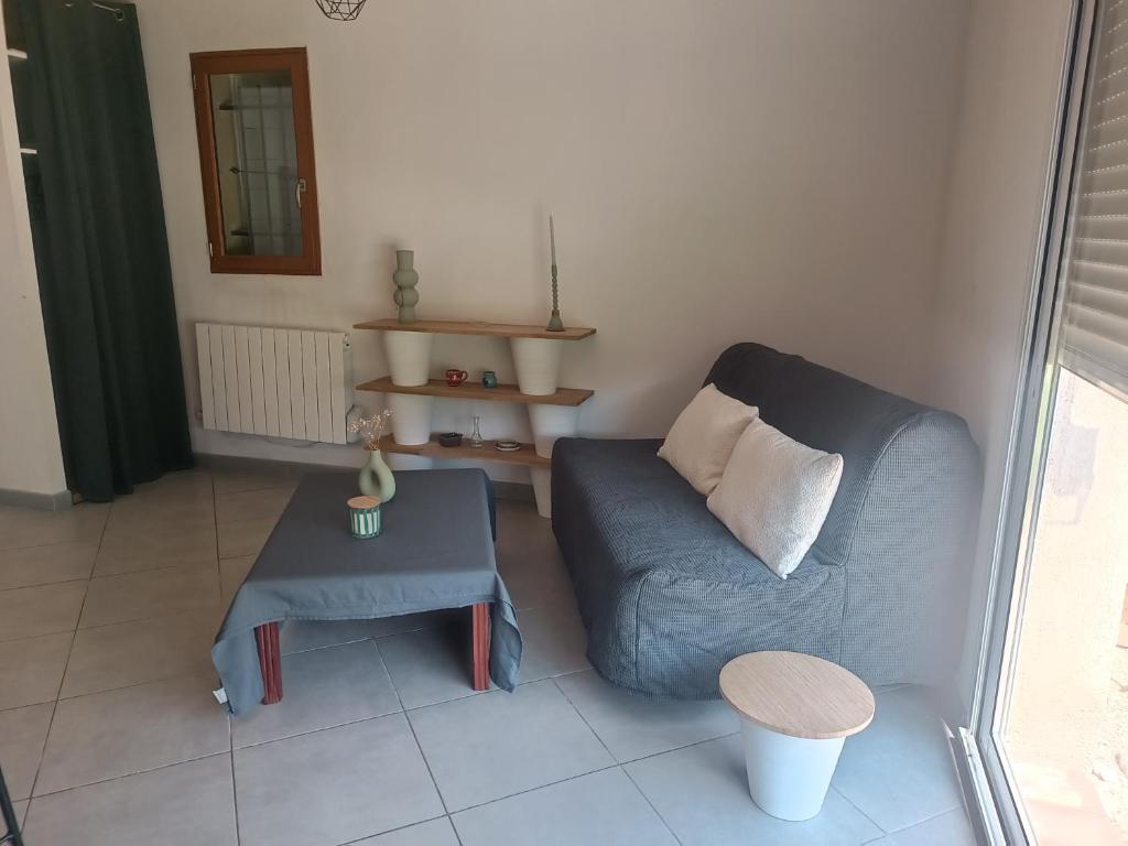 un salon avec un canapé bleu et une table dans l'établissement Maisonnette dans hameau provençal, à Cabriès