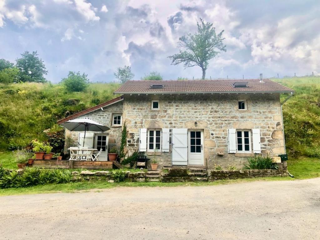 une maison en pierre avec une table et un parasol dans l'établissement Lac de Vassivière Petite maison à proximité, à Saint-Julien-le-Petit