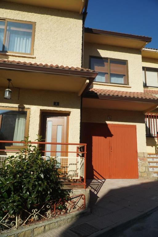 a house with an orange door and a fence at Chalet Avenida El Barraco Avila in El Barraco