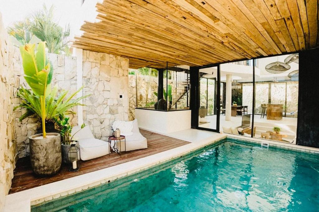 an indoor swimming pool with a house at Villa KHAYA Seminyak Stylish 2-Bedroom Villa Just 900m from the Beach in Badung