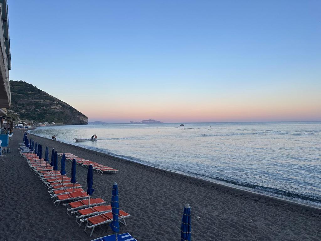 a beach with a row of chairs and the ocean at Hotel Regina del Mare in Ischia