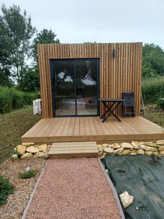une petite maison avec une terrasse en bois et une table dans l'établissement Le Refuge Des Loups, à Biziat