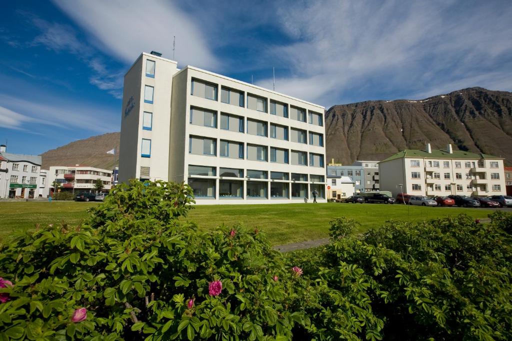 a large white building with a mountain in the background at Hotel Isafjördur - Torg in Ísafjörður
