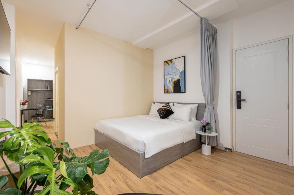 a bedroom with a white bed and a door at Manuka Home in Ho Chi Minh City