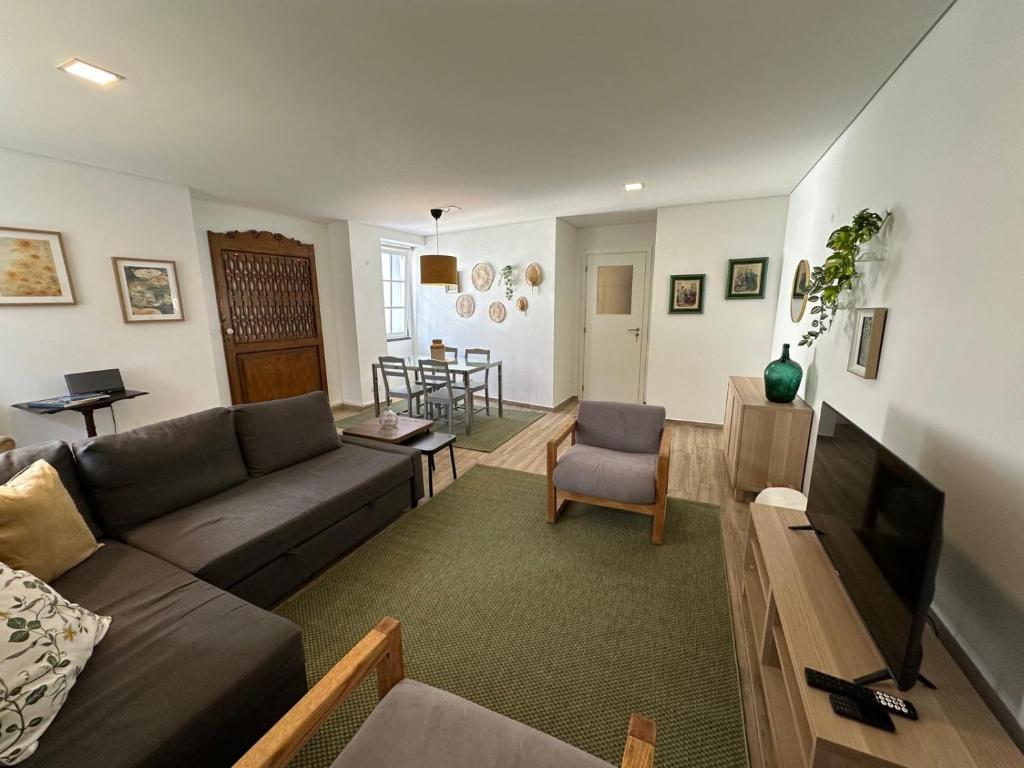 ein Wohnzimmer mit Sofa und Fernseher in der Unterkunft Casa da Joana T2 no Centro Histórico de Angra in Angra do Heroísmo