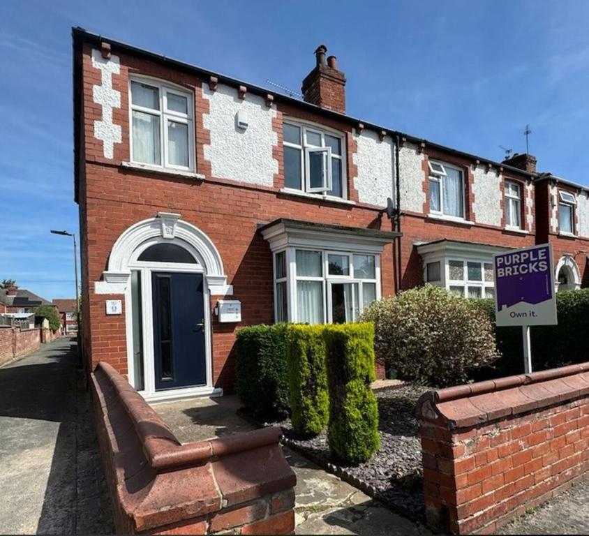una casa de ladrillo con un cartel delante de ella en Wentworth Stay l 3BHK, en Doncaster