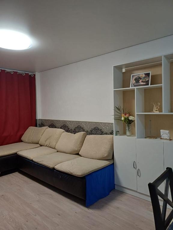 ein Sofa im Wohnzimmer mit einem roten Vorhang in der Unterkunft 2х комнатная in Zhezdi