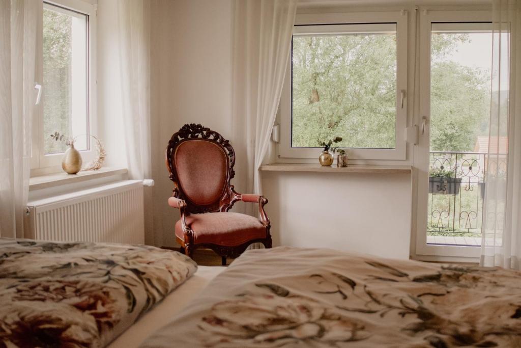 - une chambre avec une chaise, un lit et des fenêtres dans l'établissement Idyllisch gelegene Ferienwohnung Xaver im Herzen des bayerischen Waldes, à Zachenberg