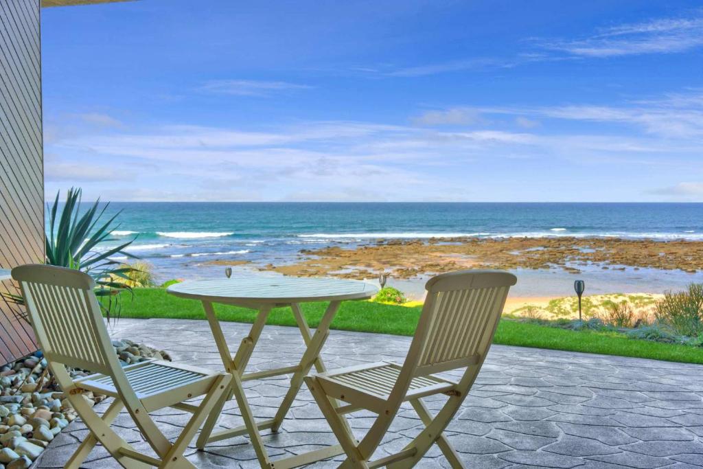 a table and two chairs sitting on a patio with the ocean at Absolute Beachfront l Couples Getaway in Blue Bay 
