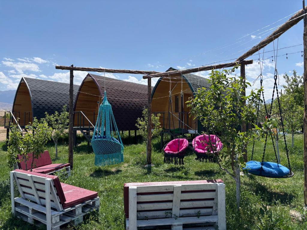 a group of chairs and swings in front of a house at Guesthouse Snow Leopard - 'Ak Ilbirs' in Tong