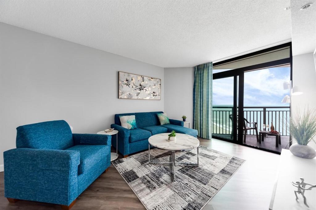 a living room with a blue couch and a table at Fabulous Angled Oceanfront Suite! CR1701 in Myrtle Beach