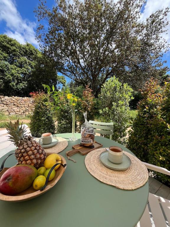 - une table avec deux assiettes de fruits et une tasse de café dans l'établissement Rez-de-villa avec terrasse privative sur jardin, à Ajaccio