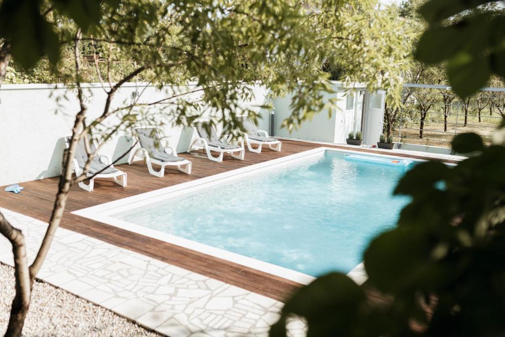 a swimming pool with lounge chairs next to a house at Almond Buna PoolHouse in Mostar