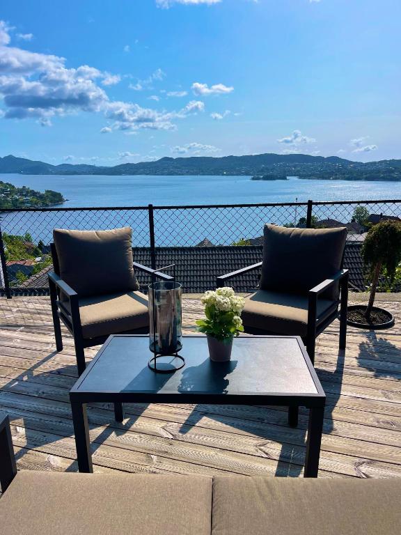 a patio with two chairs and a coffee table on a deck at 2 leiligheter med panoramautsikt in Bergen