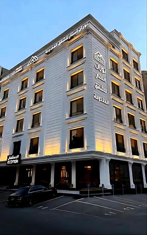 un edificio bianco con un'auto parcheggiata di fronte di نوران استار للشقق المخدومة a Gedda