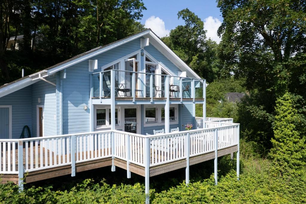 a blue house with a porch and a deck at The Bluebell - Luxury Lodge with Hot Tub in Penally