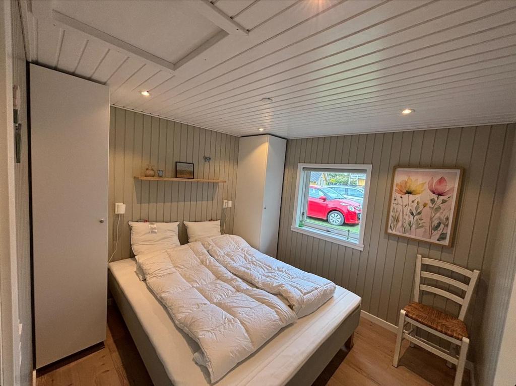 a bed in a bedroom with a window and a chair at Cozy 6 person holiday home in Juelsminde - 5 minutes walk to the beach in Sønderby