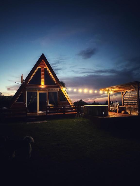a wooden house with a sunset in the background at Cabana Refugio in Bălceşti