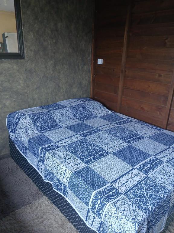 a bed with a blue and white quilt on it at Casa das Embaúbas 05 in São José