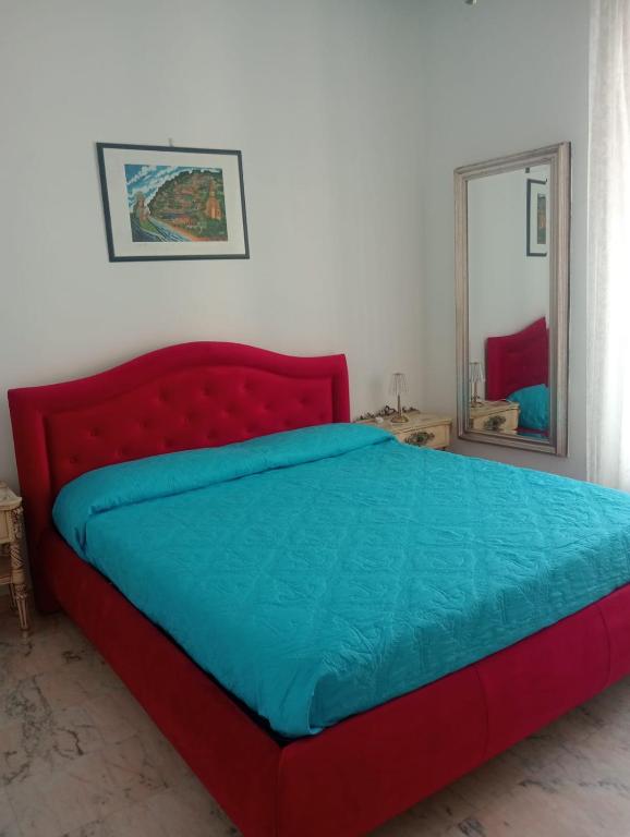 a red bed in a room with a mirror at palazzo sardanelli camera in Pizzo
