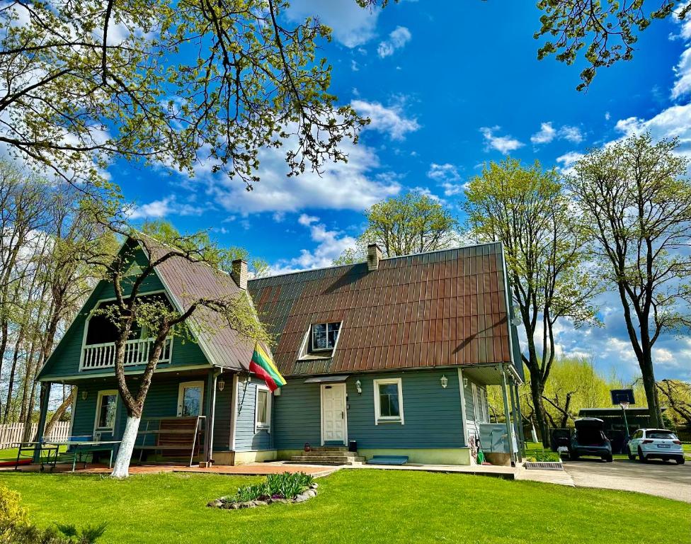 a green house with a brown roof at Maple House - Sodyba Tarp Klevų in Utena