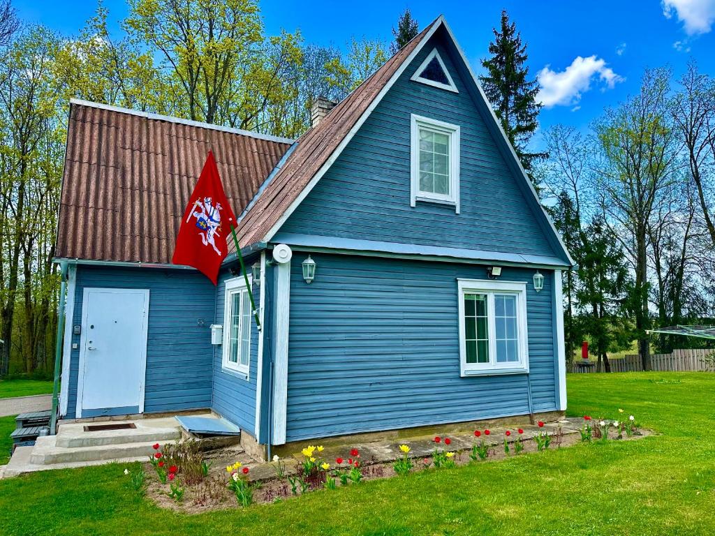 a blue house with a flag on the side of it at Maple House - Sodyba Tarp Klevų in Utena