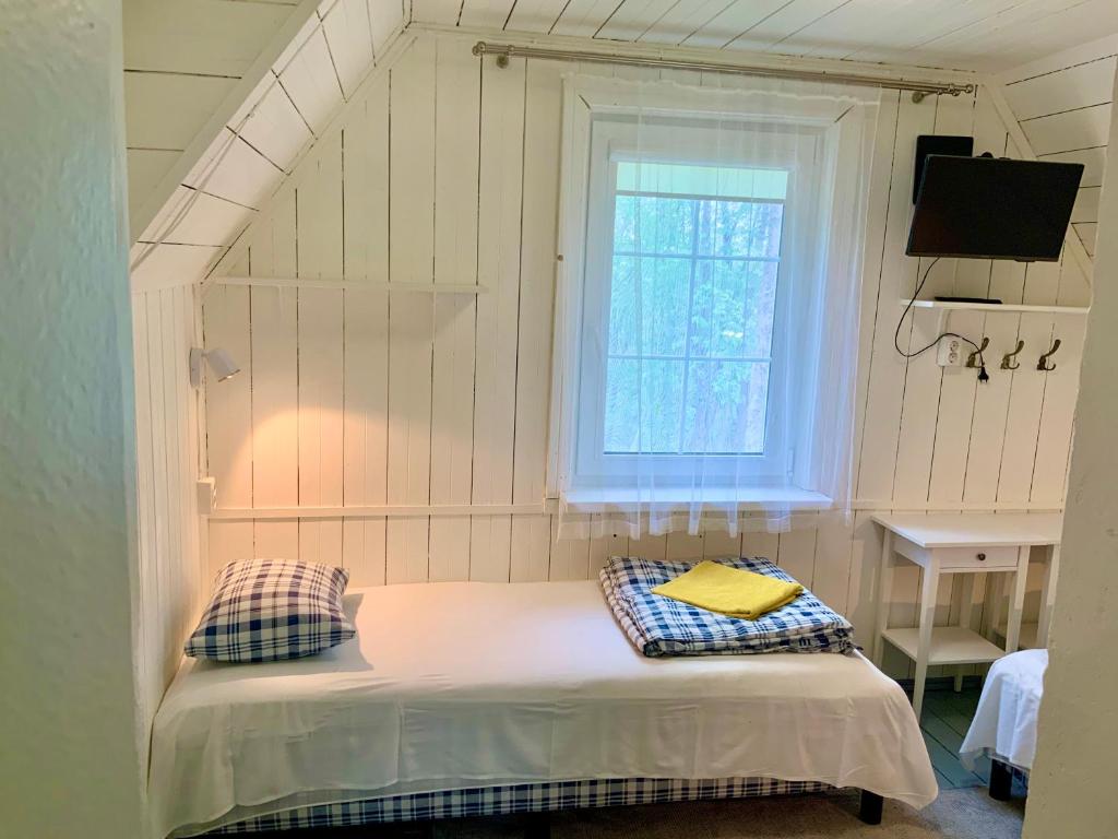 a small bed in a room with a window at Maple House - Sodyba Tarp Klevų in Utena