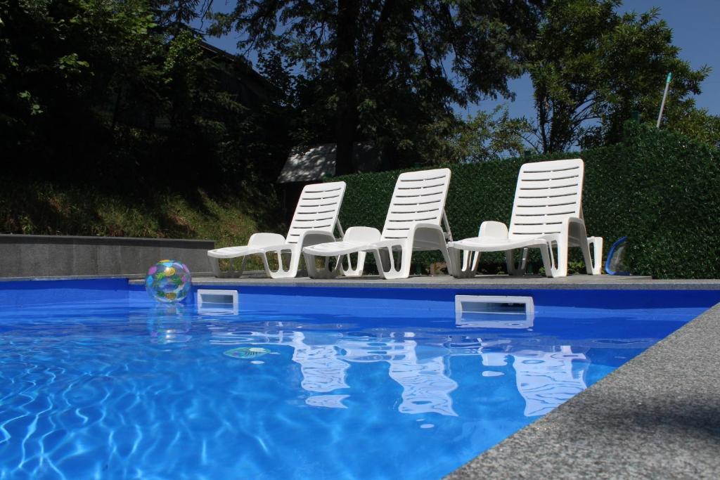 a group of white chairs and a swimming pool at Villa La Vida in Sarajevo