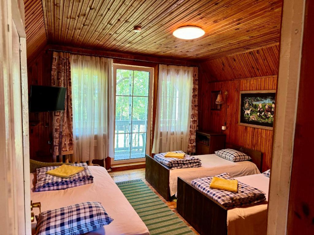 a bedroom with three beds and a window at Maple House - Sodyba Tarp Klevų in Utena