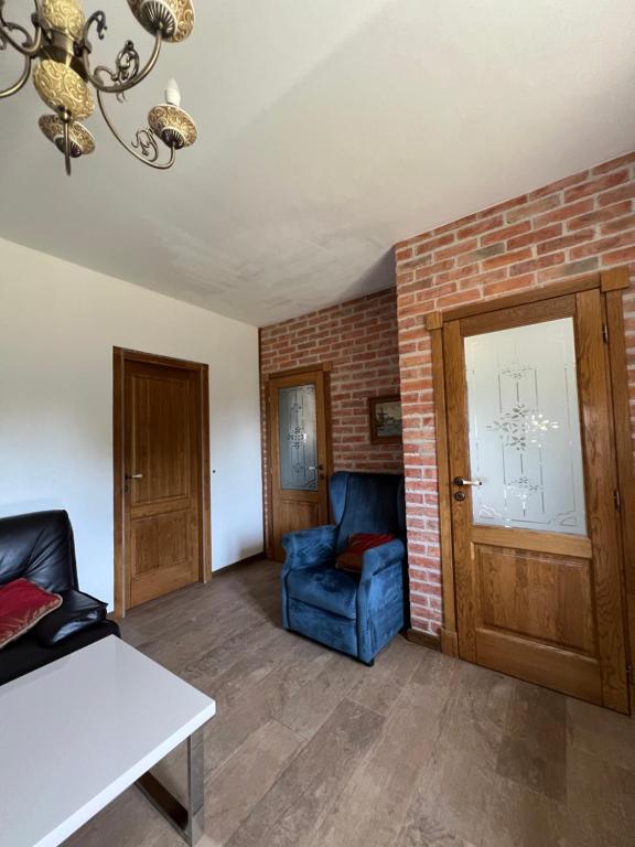 a living room with a blue chair and a brick wall at Villa SHU in Krimovice