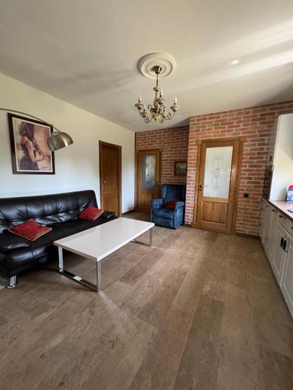 a living room with a black leather couch and a table at Villa SHU in Krimovice